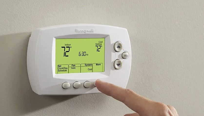 A person setting a thermostat